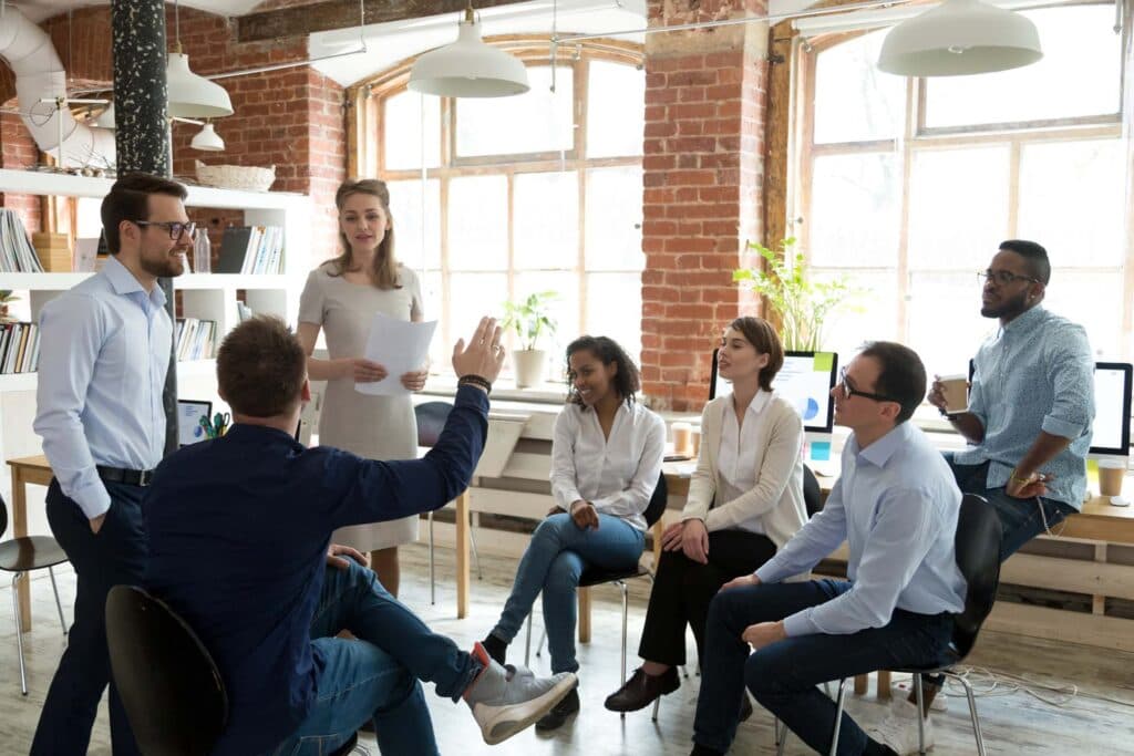 Team im Gesprächskreis bei einem Workshop in einem hellen Büro mit Backsteinwänden