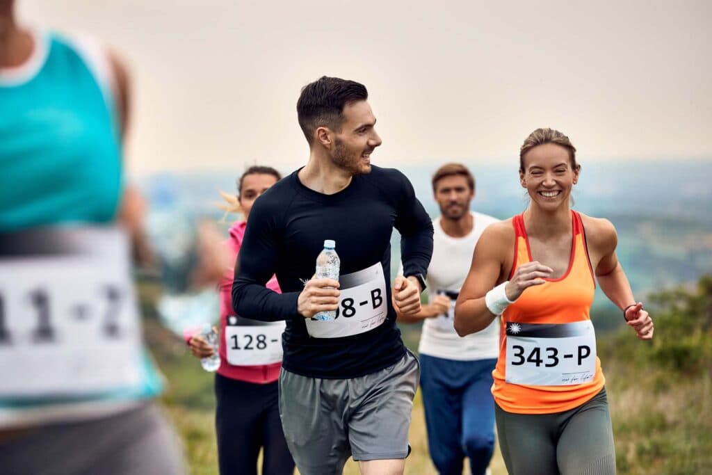 Lächelnde Läuferinnen und Läufer mit Startnummern bei einem Spendenlauf im Grünen