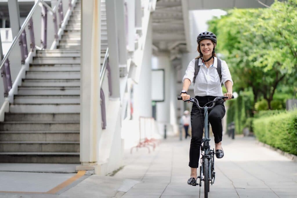 Frau mit Helm und Rucksack fährt mit dem Fahrrad zur Arbeit
