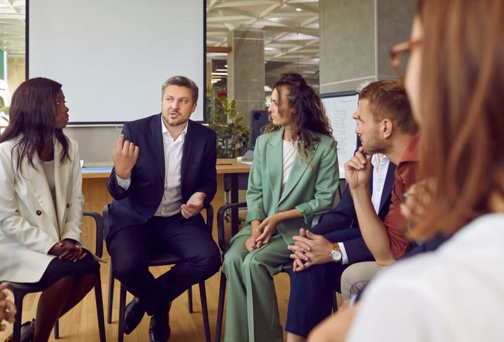 Geschäftsleute sitzen im Stuhlkreis und diskutieren in einem Workshop